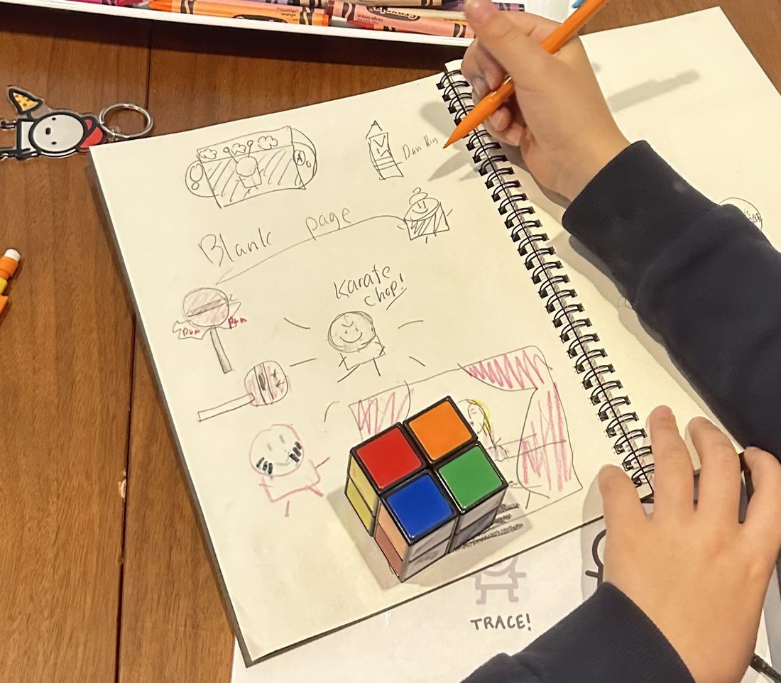 Emi sketching a Rubik's cube in her notebook